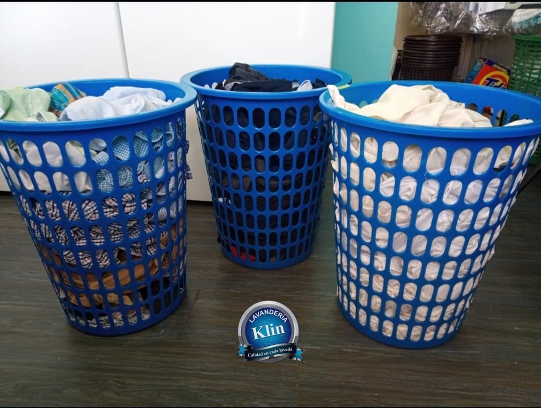 Tres hampers azules de Lavanderia Klin llenos de ropa suelta
